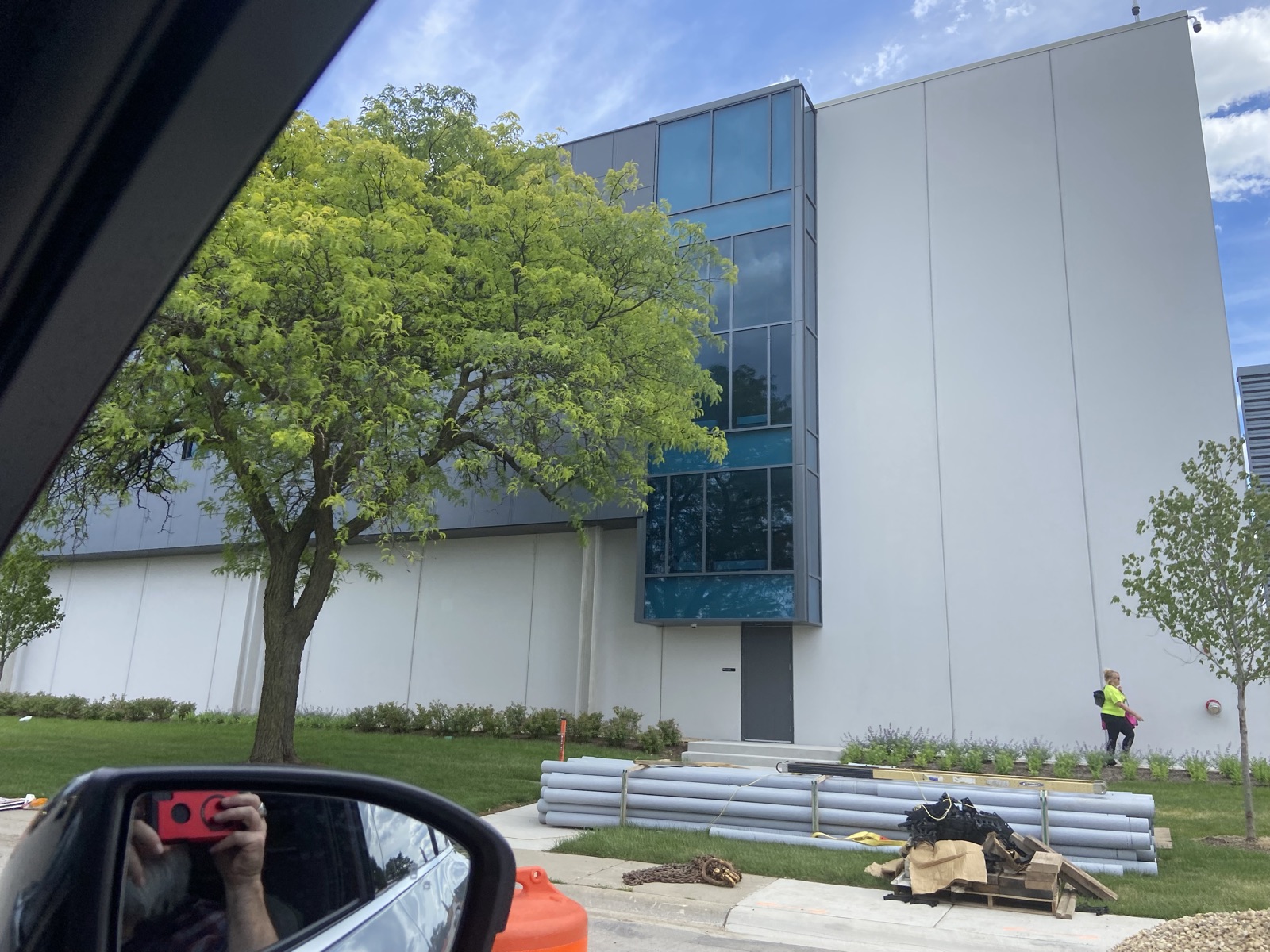 A modern, glass-fronted data center building in Elk Grove Village, Illinois, with landscaping and a worker walking outside.